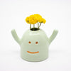 Ceramic monster-shaped vase with yellow flowers on a white background