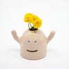 Ceramic monster-shaped vase with yellow flowers on a white background