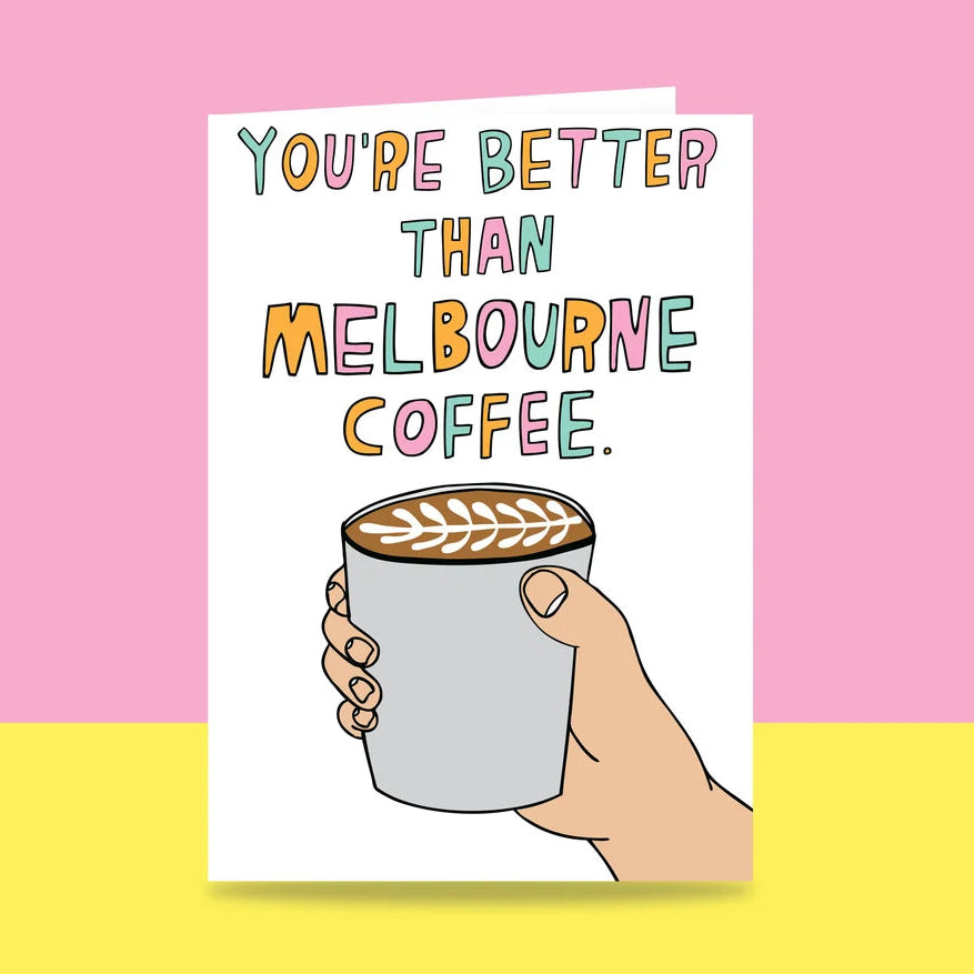 A greeting card with the text 'YOU'RE BETTER THAN MELBOURNE COFFEE.' in colourful hand-drawn letters above an illustration of a hand holding a cup of coffee with latte art, shown against a pink and yellow split background.