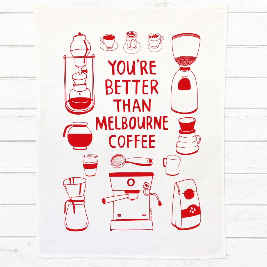 A white kitchen towel featuring red line drawings of coffee-related items and the text 'YOU'RE BETTER THAN MELBOURNE COFFEE' in red, displayed flat against a white wood plank background.