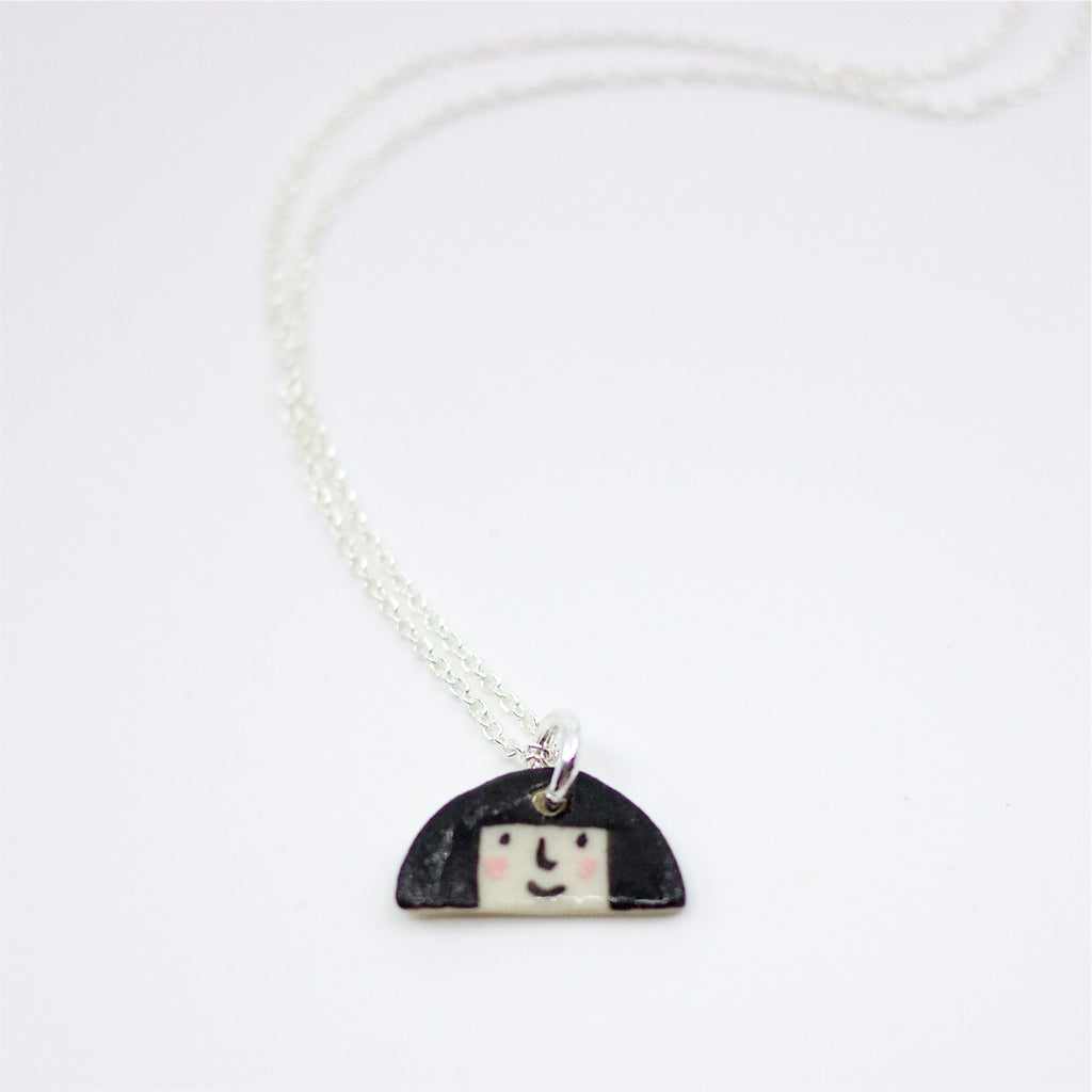 Sterling silver necklace featuring a hand-painted ceramic pendant with a fun, expressive face and large hair design, displayed on a white background.