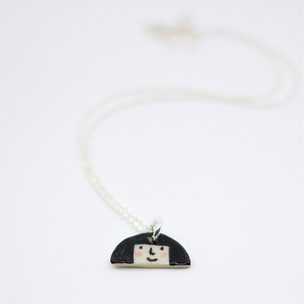 Sterling silver necklace featuring a hand-painted ceramic pendant with a fun, expressive face and large hair design, displayed on a white background.