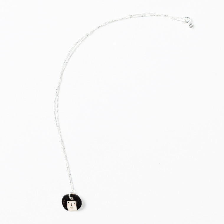 Sterling silver necklace featuring a hand-painted ceramic pendant with a character face and bob hairstyle, displayed on a white background.
