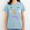 A model wearing the boo tee. Blue coloured tee, with a stylised face with tongue poking out. 