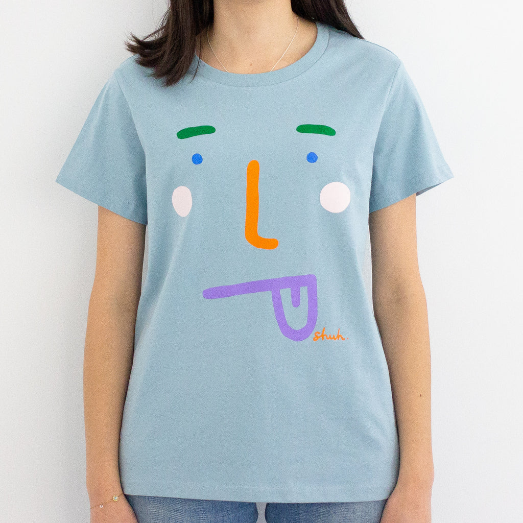 A model wearing the boo tee. Blue coloured tee, with a stylised face with tongue poking out. 