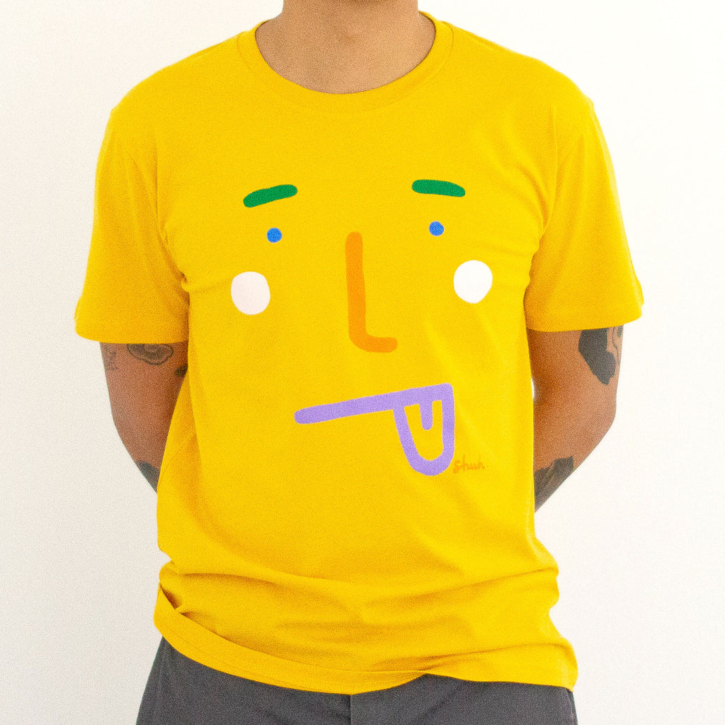 A model wearing the boo tee. Blue coloured tee, with a stylised face with tongue poking out. 
