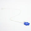Sterling silver necklace featuring a bright blue ceramic flower-shaped pendant with a polkadot pattern in the centre, displayed on a white background.