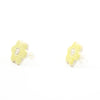 Side view of a pair of handmade ceramic stud earrings shaped like small yellow buttercup flowers, with tiny dotted details and a carved centre. Finished with sterling silver posts.