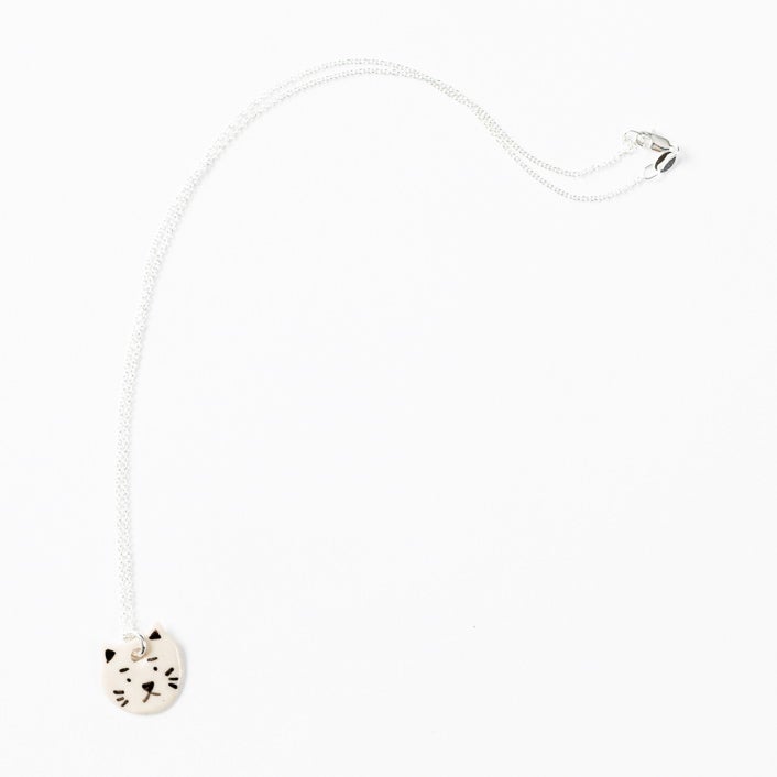 Sterling silver necklace featuring a hand-painted ceramic cat-shaped pendant with a playful expression, displayed on a white background.