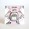 Enamel pin featuring a hand-drawn girl’s face a cat head costume, displayed on a pink card with cat illustrations and “shuh. pins” branding.
