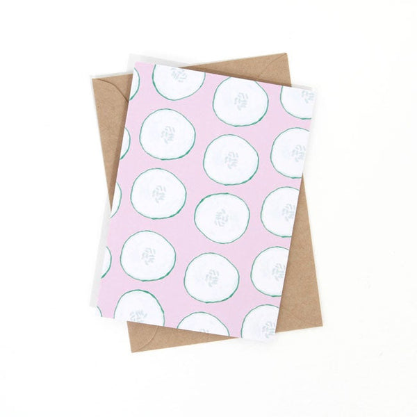 Front view of the cool as a cucumber print. Repeated cucumber slices over a pink background. 