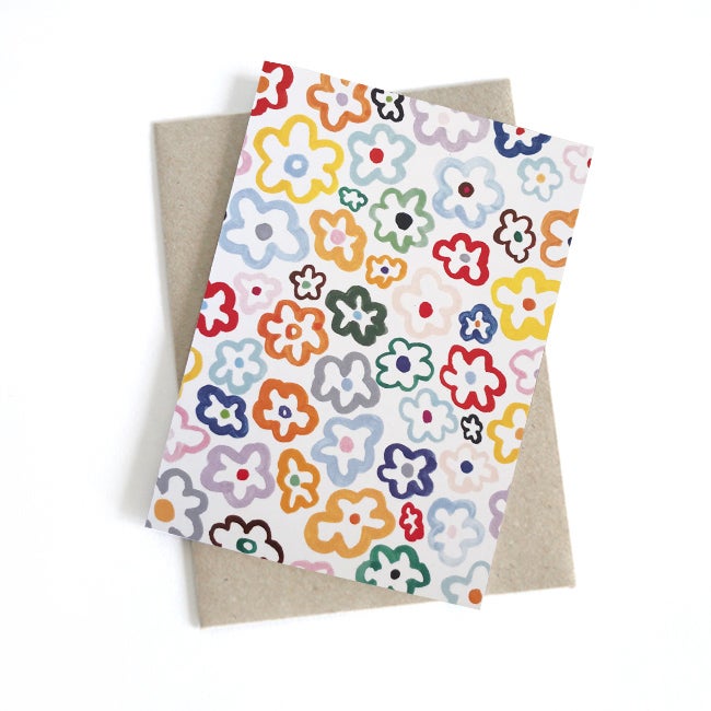 Front view of the daisy print card. Multicoloured daisies on a white background. 