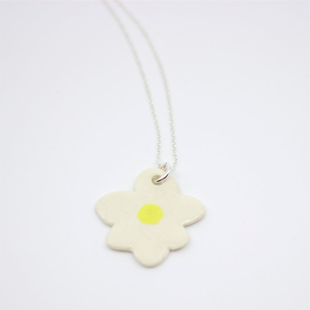 Sterling silver necklace featuring a large, hand-painted ceramic daisy-shaped pendant with black detailing on a white background.
