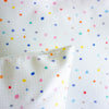 A corner detail view of the day pop cushions. Print is multicoloured polka dots on a light grid background. 