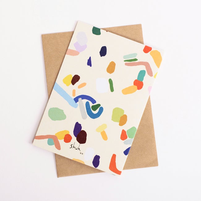 Back view of the enough card, with recycled paper envelope. Print features colourful patches and splotches. 