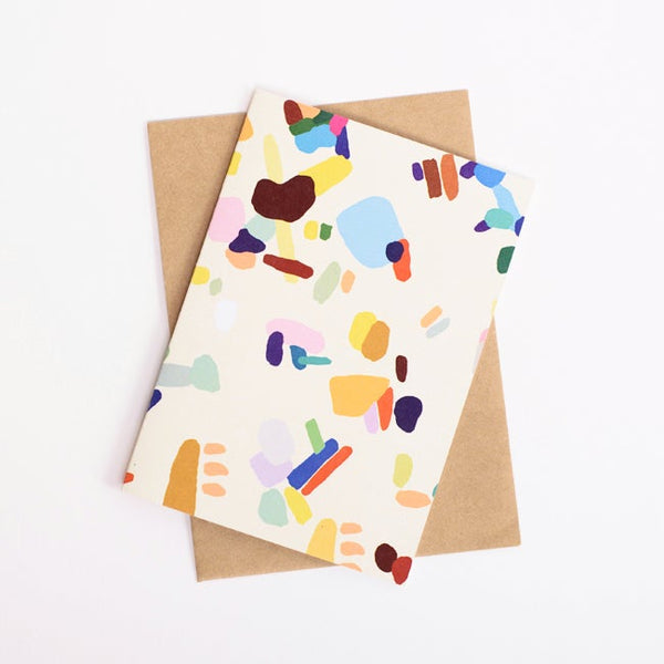 Front view of the enough card, with recycled paper envelope. Print features colourful patches and splotches. 
