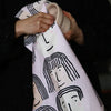 Fab faces tea towel. Different diverse faces, with different features, on a pink background. This picture shows the towel being used. 