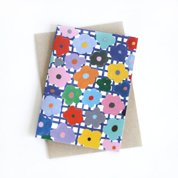 Front view of the flower print card. Multicoloured flowers on a white and blue chequered background.