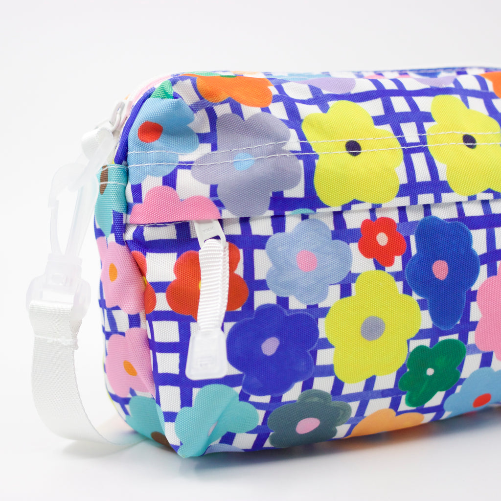 Strap view of the flower everyday bag. Bright flower illustrations over a blue and white checkered background.