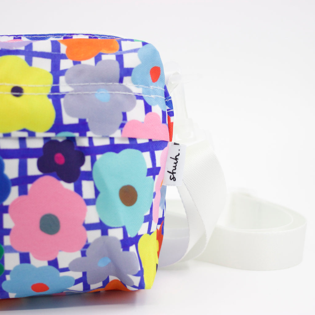 Tag view of the flower everyday bag. Bright flower illustrations over a blue and white checkered background.