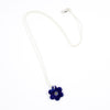 Sterling silver necklace with a hand-painted ceramic blue flower-shaped pendant, featuring black line detail, displayed on a white background.