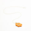 Sterling silver necklace featuring a bright orange ceramic flower-shaped pendant with a black dotted centre, displayed on a white background.