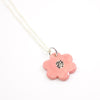 Closeup view of the Sterling silver necklace with a hand-painted pink ceramic flower pendant, featuring black line detail, displayed on a white background.