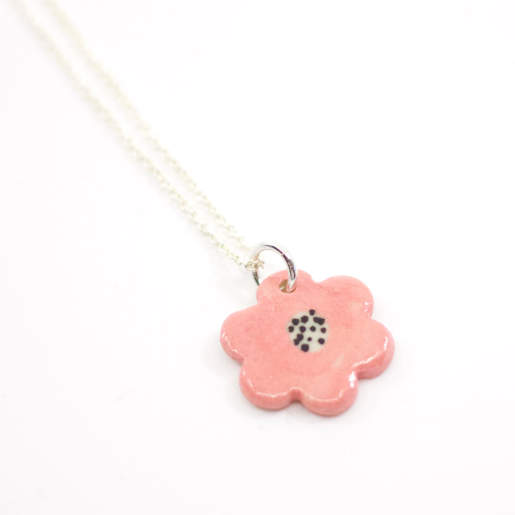 Closeup view of the Sterling silver necklace with a hand-painted pink ceramic flower pendant, featuring black line detail, displayed on a white background.