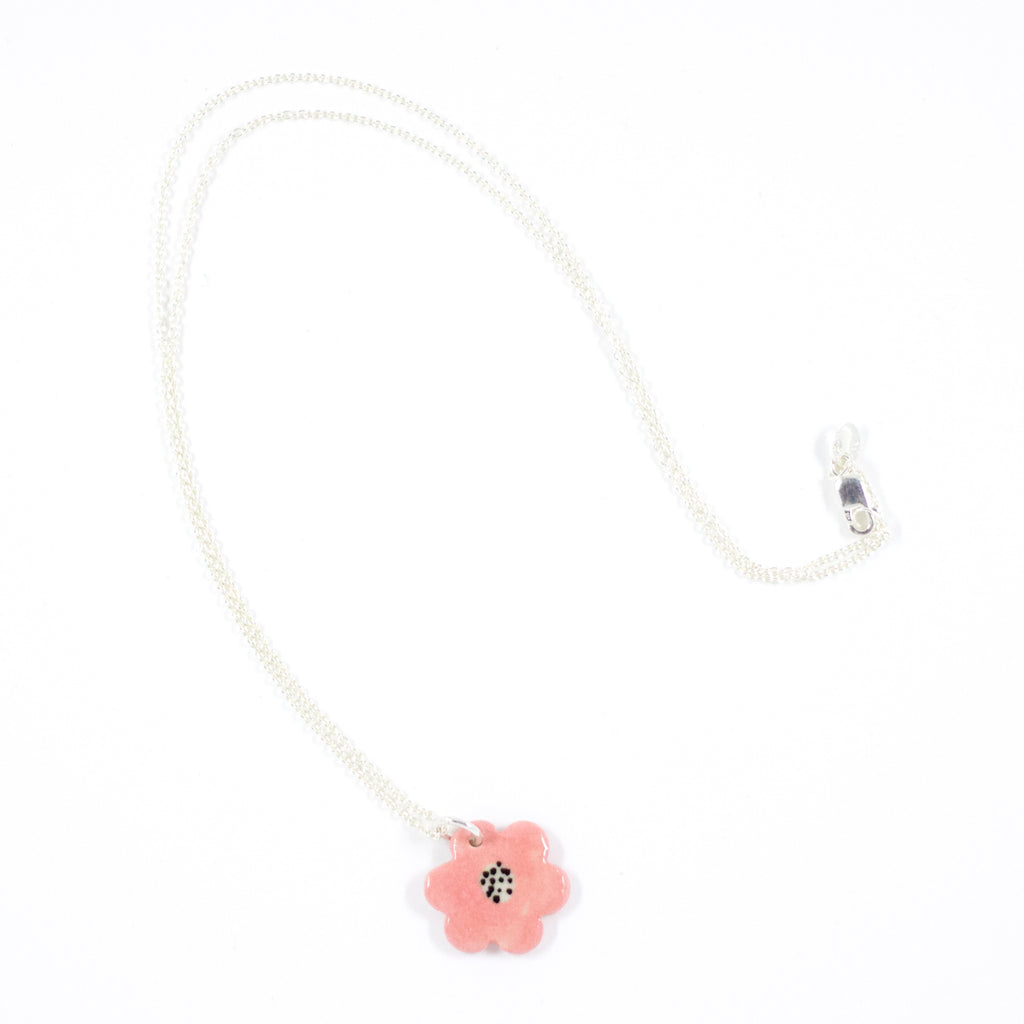 Sterling silver necklace with a hand-painted pink ceramic flower pendant, featuring black line detail, displayed on a white background.