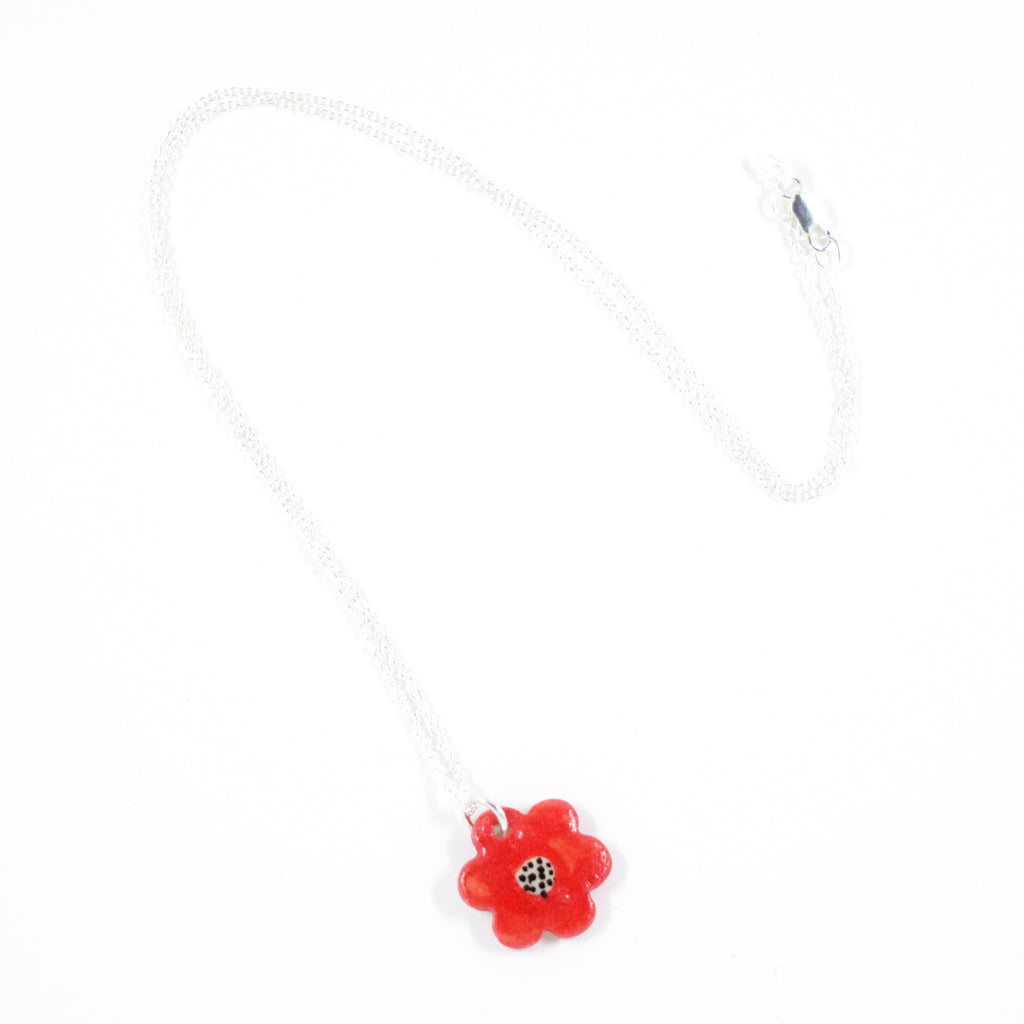 Sterling silver necklace featuring a red hand-painted ceramic flower pendant with black line detailing, displayed on a white background.