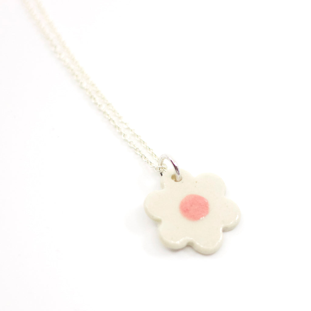 Closeup view of the Sterling silver necklace featuring a hand-painted white ceramic flower-shaped pendant, displayed on a white background.
