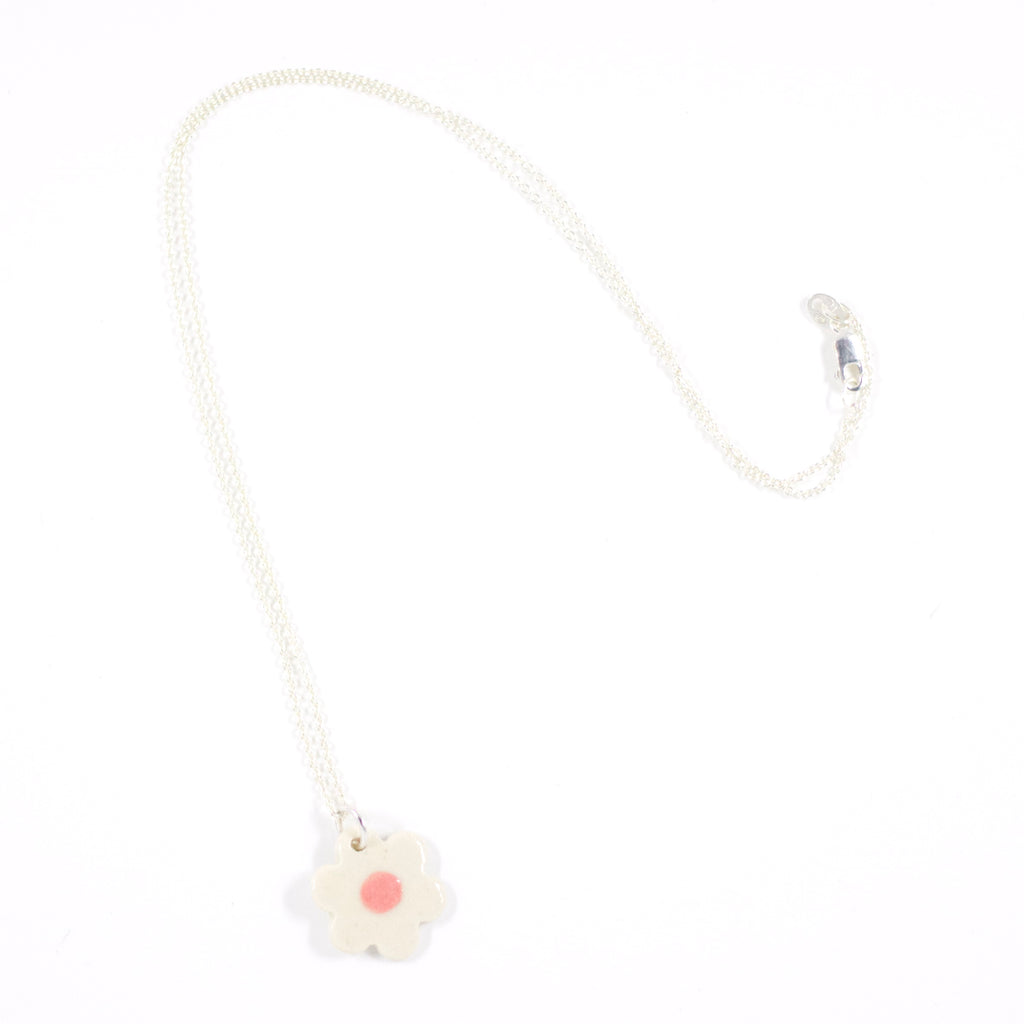 Sterling silver necklace featuring a hand-painted white ceramic flower-shaped pendant, displayed on a white background.