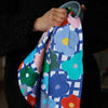 The flower tea towel, in use drying a bowl. Bright multicoloured flowers on a blue and white chequered background. 
