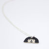 Sterling silver necklace featuring a hand-painted ceramic pendant with a playful face and fuzzy hairstyle, displayed on a white background.