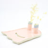 Side view of the ghost trinket dish. Two spouts hold flowers. Dish is ghost shaped. Pink colour, and a cutout smile. 