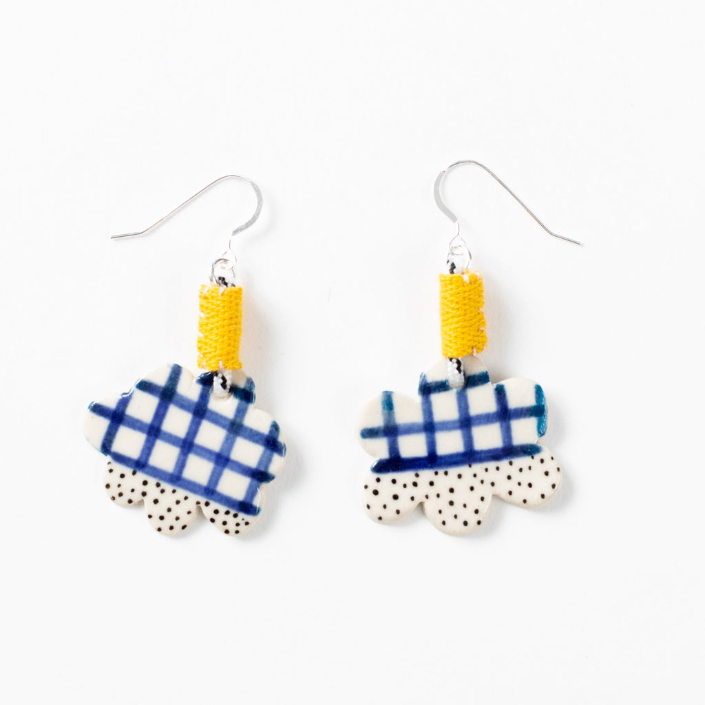 Cloud shaped ceramic bead earrings with rope attachment stitched with yellow fabric binding. Ceramic bead has blue lines and black spots patterns on it. 