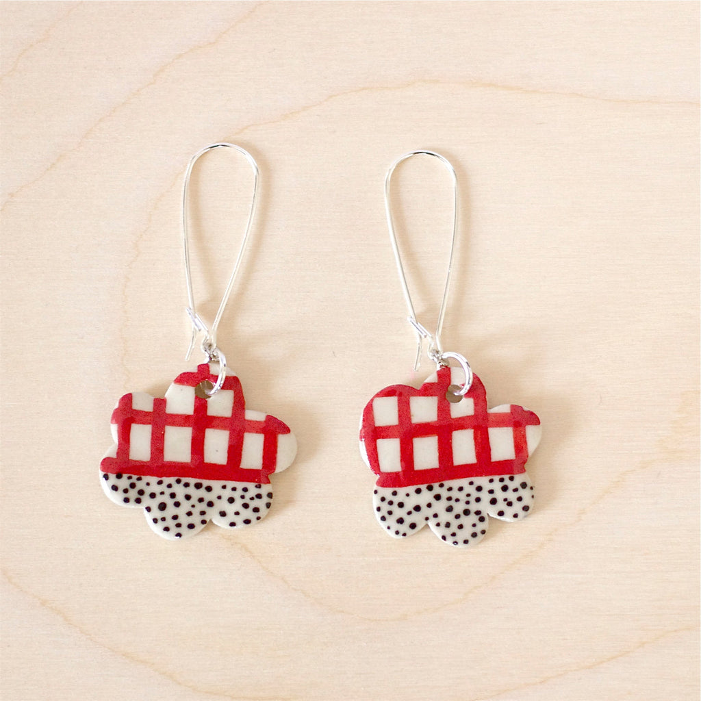 Cloud shaped ceramic bead earrings with rope attachment stitched with yellow fabric binding. Ceramic bead has red lines and black spots patterns on it. 
