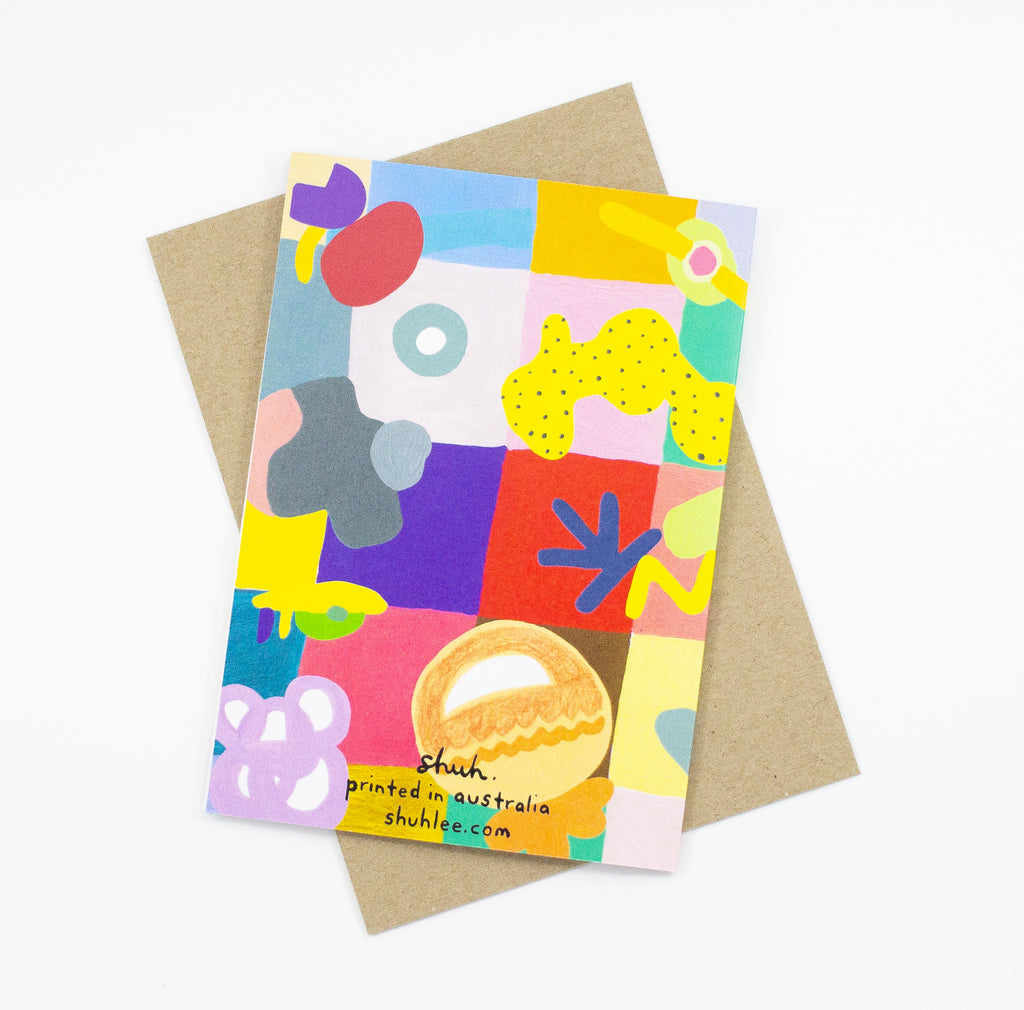 Back view of the Joy Mat print card. Abstract shapes, characters, and bright colours over a background of multicoloured sqaures. 