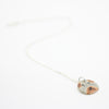 Sterling silver necklace featuring a round ceramic pendant hand-painted with a dog’s face in beige and brown tones, displayed on a white background.
