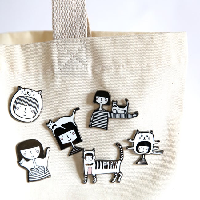 Photo of the collection of cat pins, all attached to a linen tote bag. 