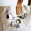 closeup of the 3 dog pins from the shuh pin collection. Attached to a bag. 