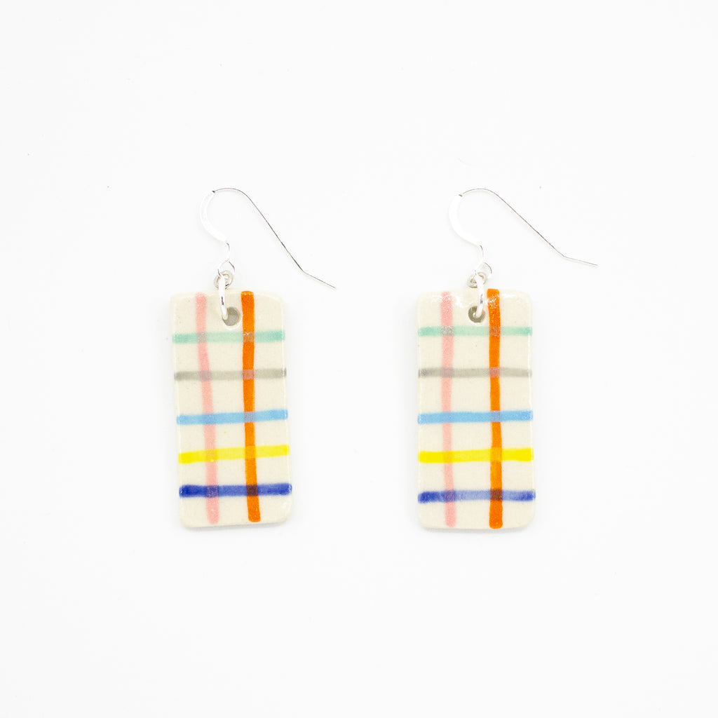 A pair of handmade ceramic earrings with rectangular tiles, painted with a grid of colourful stripes in red, blue, yellow, pink, orange, green, and grey. Finished with silver hooks for pierced ears.