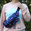 Salad bumbag being carried overshoulder by model. Print has multicoloured flowers on a navy background.