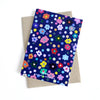 Front view of the Salad card. Multicoloured flower heads and polka dots on a navy background.