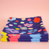 Front view of the Salad napkin set. Bold flower patterns and polka dots, with all shuh.’s favourite colours, on a navy background