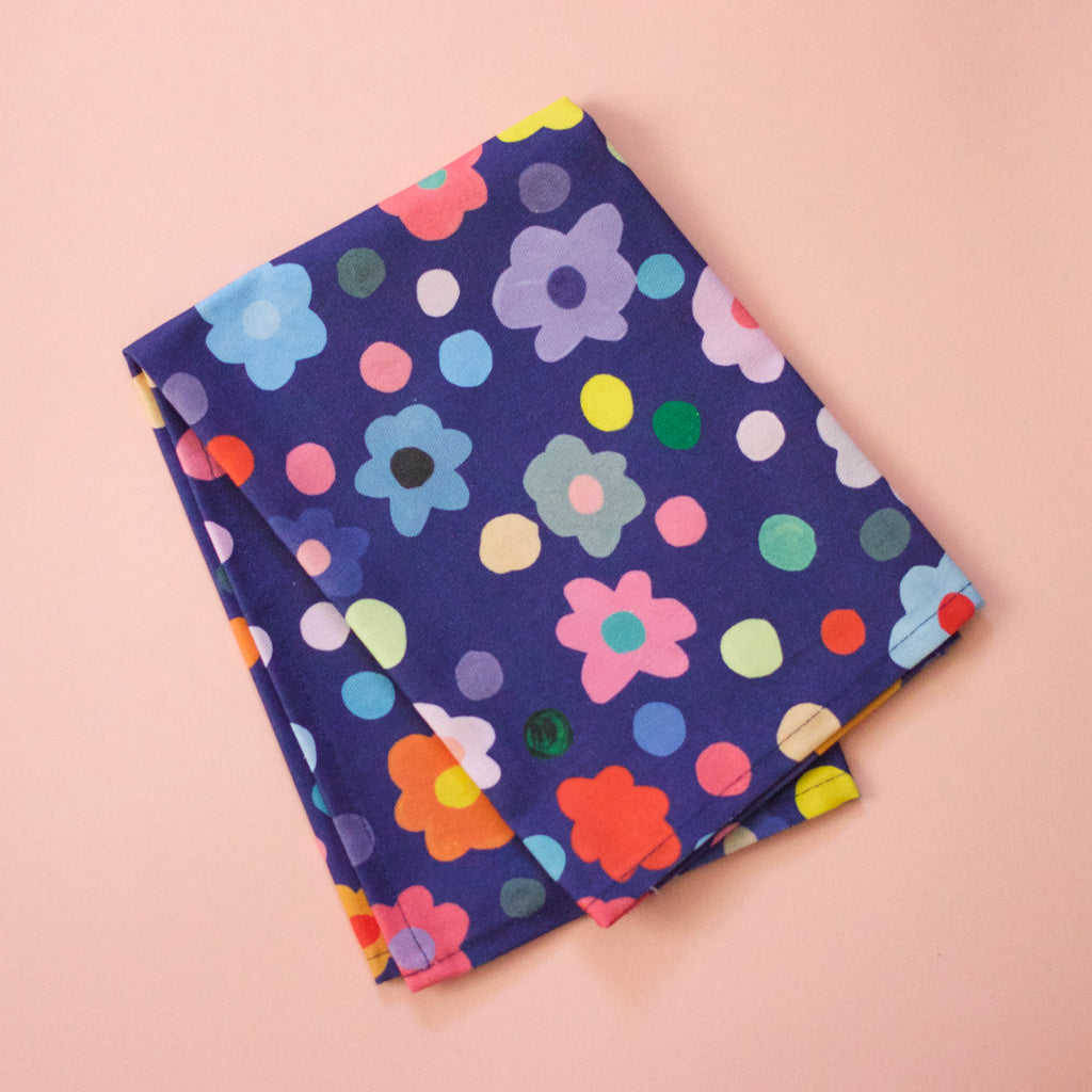 Top view of the salad napkin. Bold flower patterns and polka dots, with all shuh.’s favourite colours, on a navy background