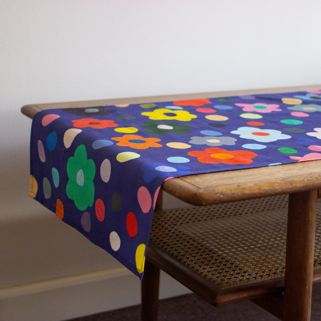 End view of the Salad table runner. Bold flower patterns and polka dots, with all shuh.’s favourite colours, on a navy background