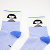 A closeup cuff view of the shuh. girl socks. Featuring the iconic shuh. girl and a blue and white striped pattern, these socks are designed to bring fun and imagination to your feet