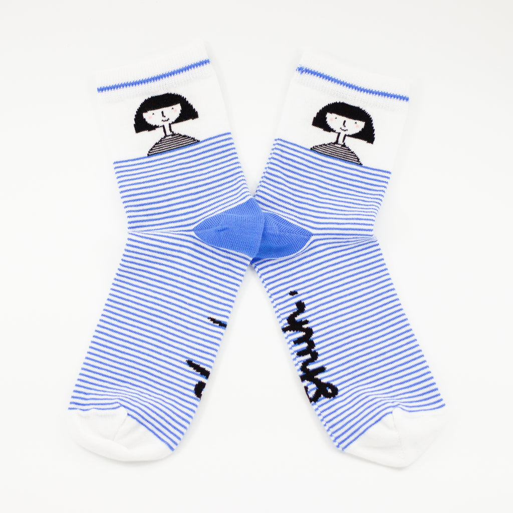 Front view of the shuh. girl socks. Featuring the iconic shuh. girl and a blue and white striped pattern, these socks are designed to bring fun and imagination to your feet