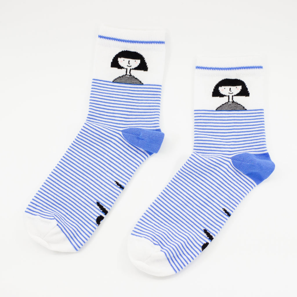 Side by side view of the shuh. girl socks. Featuring the iconic shuh. girl and a blue and white striped pattern, these socks are designed to bring fun and imagination to your feet